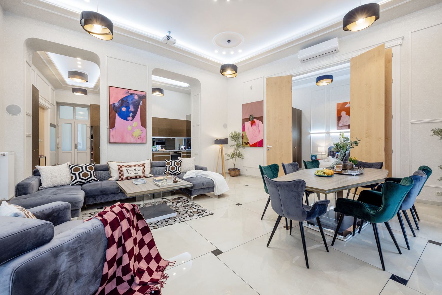 Living room with colorful figurative art and green velvet dining chairs