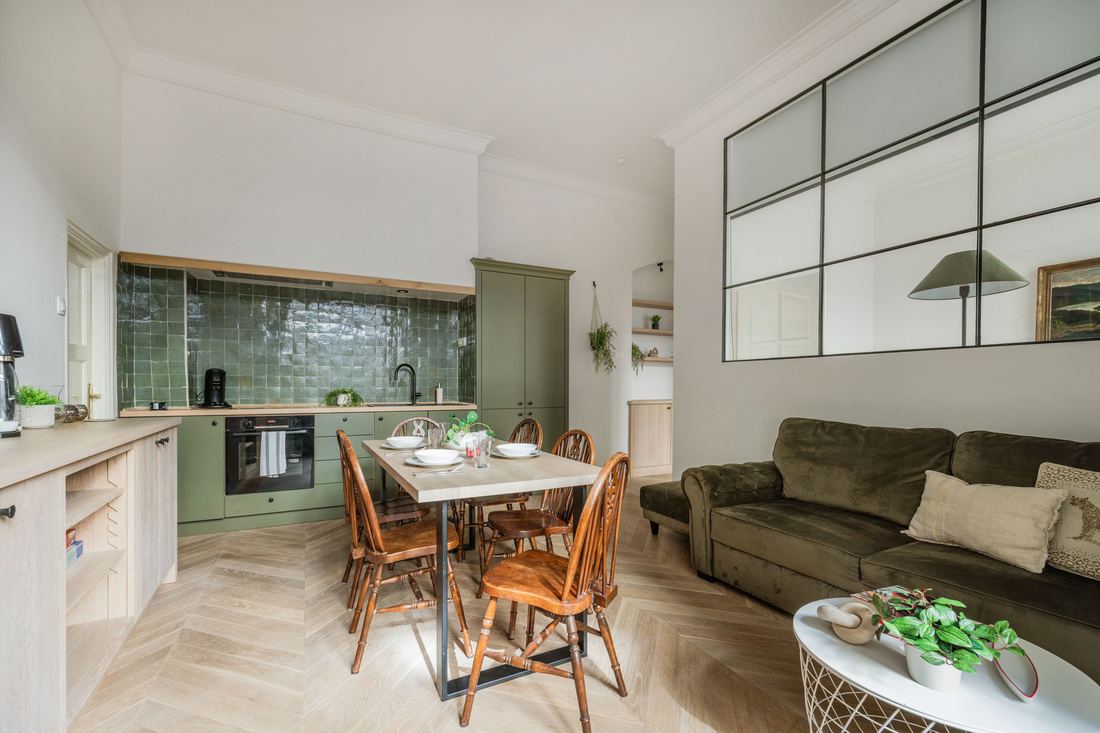 Green-tiled kitchen opening onto a warm dining and living space